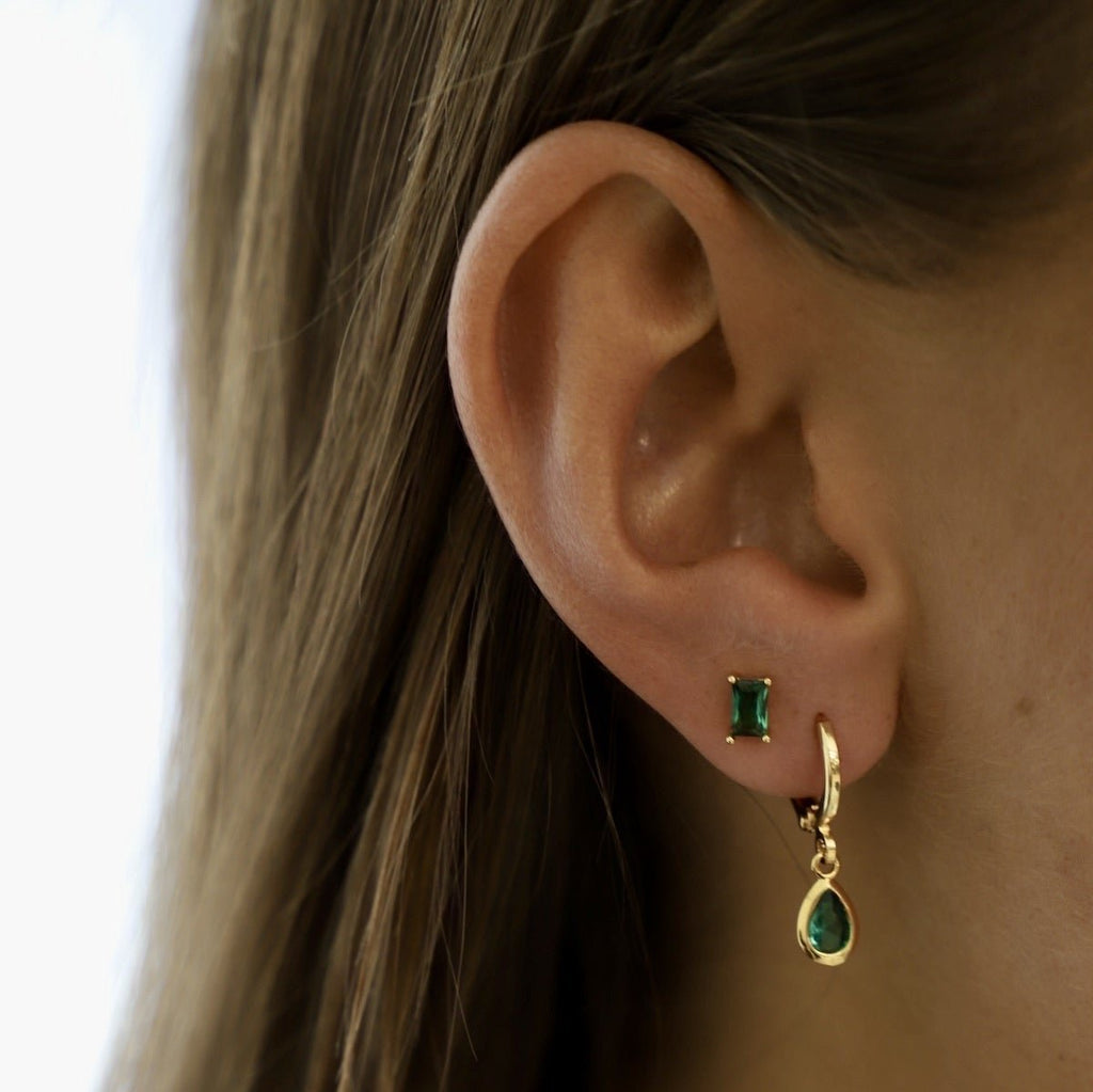 Our Emerald CZ Studs are glamorous and classic. With a baguette cut emerald jewel sitting on a sterling silver post they have just the right amount of colorful sparkle. They are easy to use as a layering piece in your first or second earring hole!