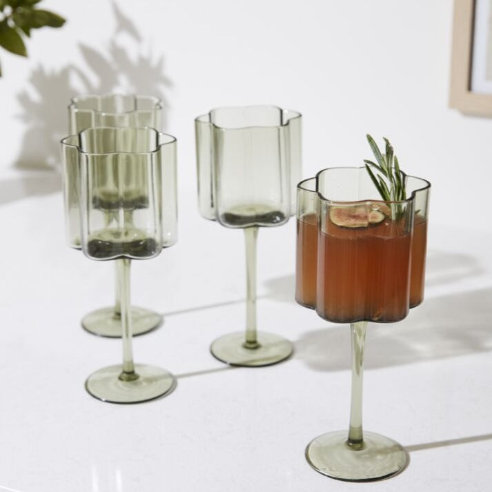 As decorative as it is functional, the stemmed Floret Wine Glass is right at home styled on bar carts or open kitchen shelving. This trendy handmade solid glass drinkware elevates any cocktail party, event, or home bar with its smoky grey hue, scalloped rim, &amp; vertical ridging. Food &amp; dishwasher safe, this glass is even more beautiful arranged alongside the whole Floret glassware family.