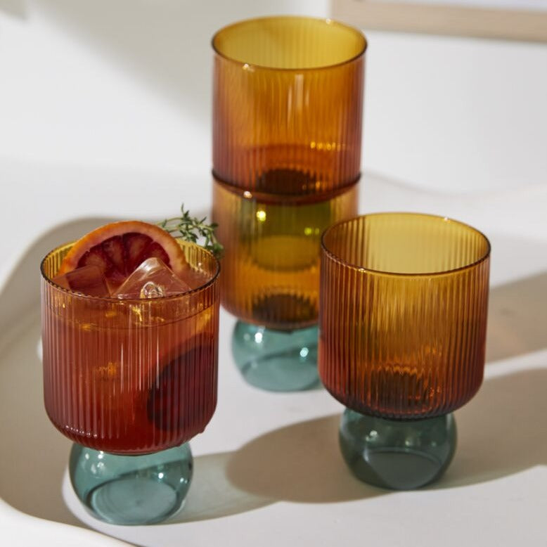 Full of fun, clever details &amp; bold color, the Felix Drinkware brings an elevated yet playful look to tableware. Handmade from lightweight, solid borosilicate glass, this drinking glass is two-toned with a ribbed amber top &amp; smooth, ball-shaped turquoise foot. Style this chic vessel on a bar cart or open kitchen shelving to show off its trendy, unique design while adding a pop of color to home decor.&nbsp;