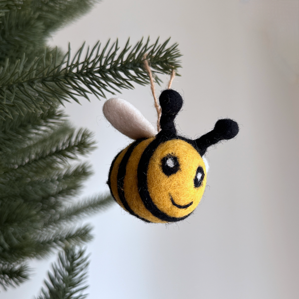 Looking to add some holiday cuteness to your decor? Look no further than our bee ornament! Made of felted wool, featuring a cheerful yellow and black design and adorable wings, this little buzzer is guaranteed to bring a smile to your face. Don't miss out - get yours today!