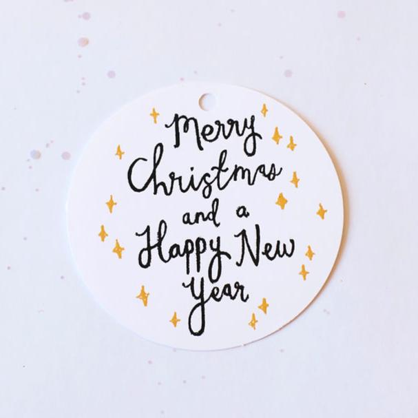 white circle gift tag reading "merry christmas and a happy new year" covered in yellow twinkling stars