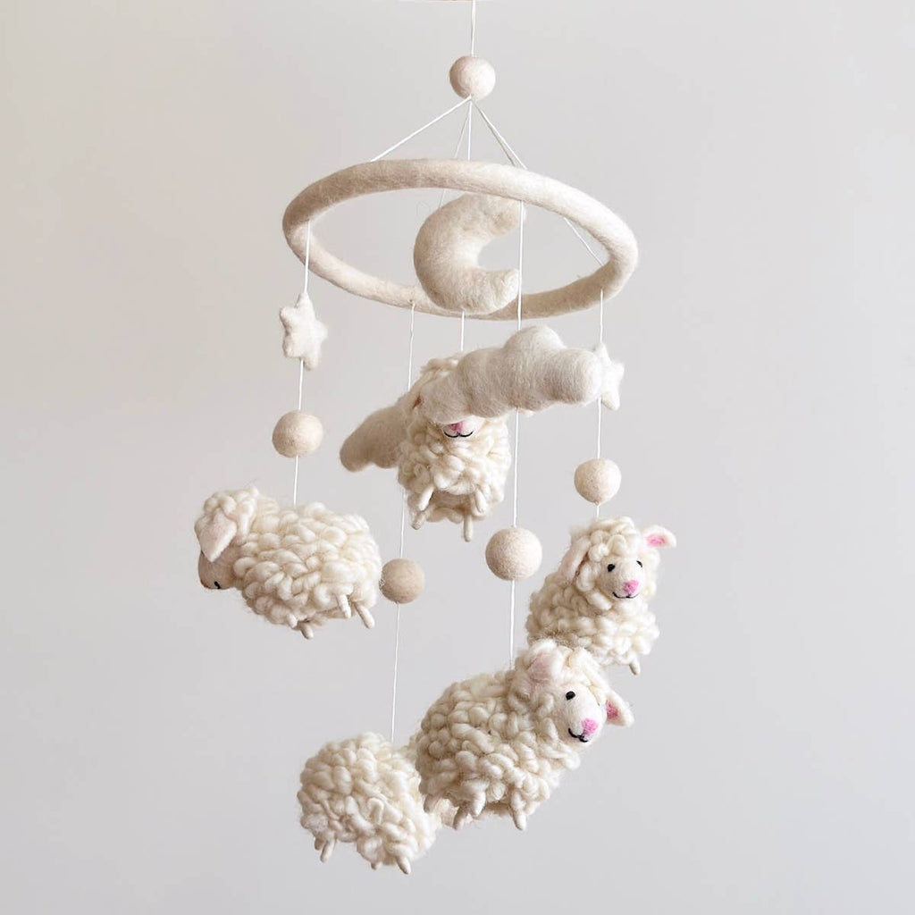 Introducing our "Fluffy Sheep Mobile" – a touch of bedtime magic for your little one. Crafted with fluffy sheep's fur, each sheep has a pink nose and ear, mirroring the softness of dreams. Five charming sheep adorned with stars, clouds, and a moon create a celestial scene that lulls your baby to sleep. Let this mobile whisk your baby off to dreamland with its cozy charm and soothing presence.