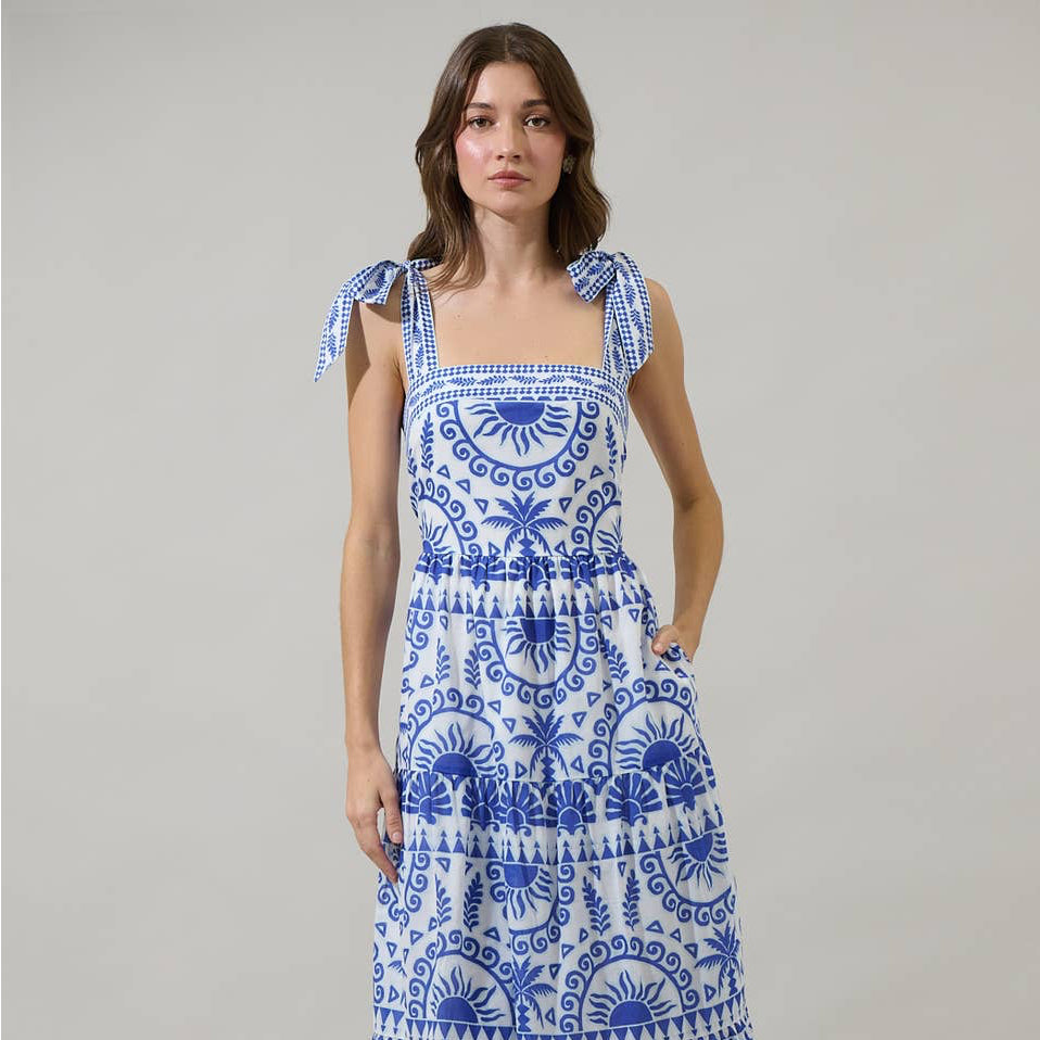 It’s easy to create a cute look when you’ve got the Rivera Tropics Emely Tiered Maxi Dress. A blue print sits on a white background creating this fun and creative print. It features shoulder tie straps, tiered layers, and a smocked back. White heels would be a perfect match to this dress.