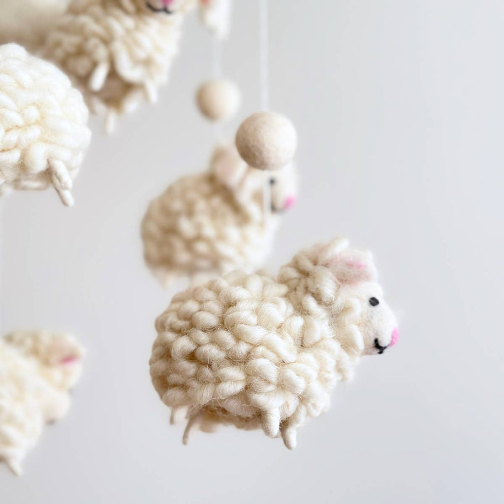 Introducing our "Fluffy Sheep Mobile" – a touch of bedtime magic for your little one. Crafted with fluffy sheep's fur, each sheep has a pink nose and ear, mirroring the softness of dreams. Five charming sheep adorned with stars, clouds, and a moon create a celestial scene that lulls your baby to sleep. Let this mobile whisk your baby off to dreamland with its cozy charm and soothing presence.