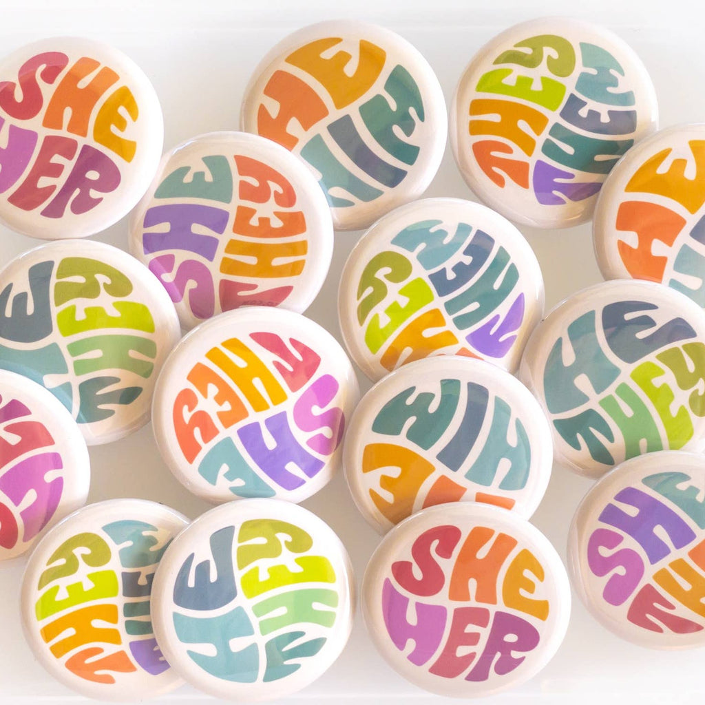 Wear your pronouns with pride with these cute retro-style buttons! This pinback button displays "They/Them" pronouns in a colorful palette. It is the perfect way to let others know how to address you and to show your support for the LGBTQ+ community!  Size: 1.25" pinback button