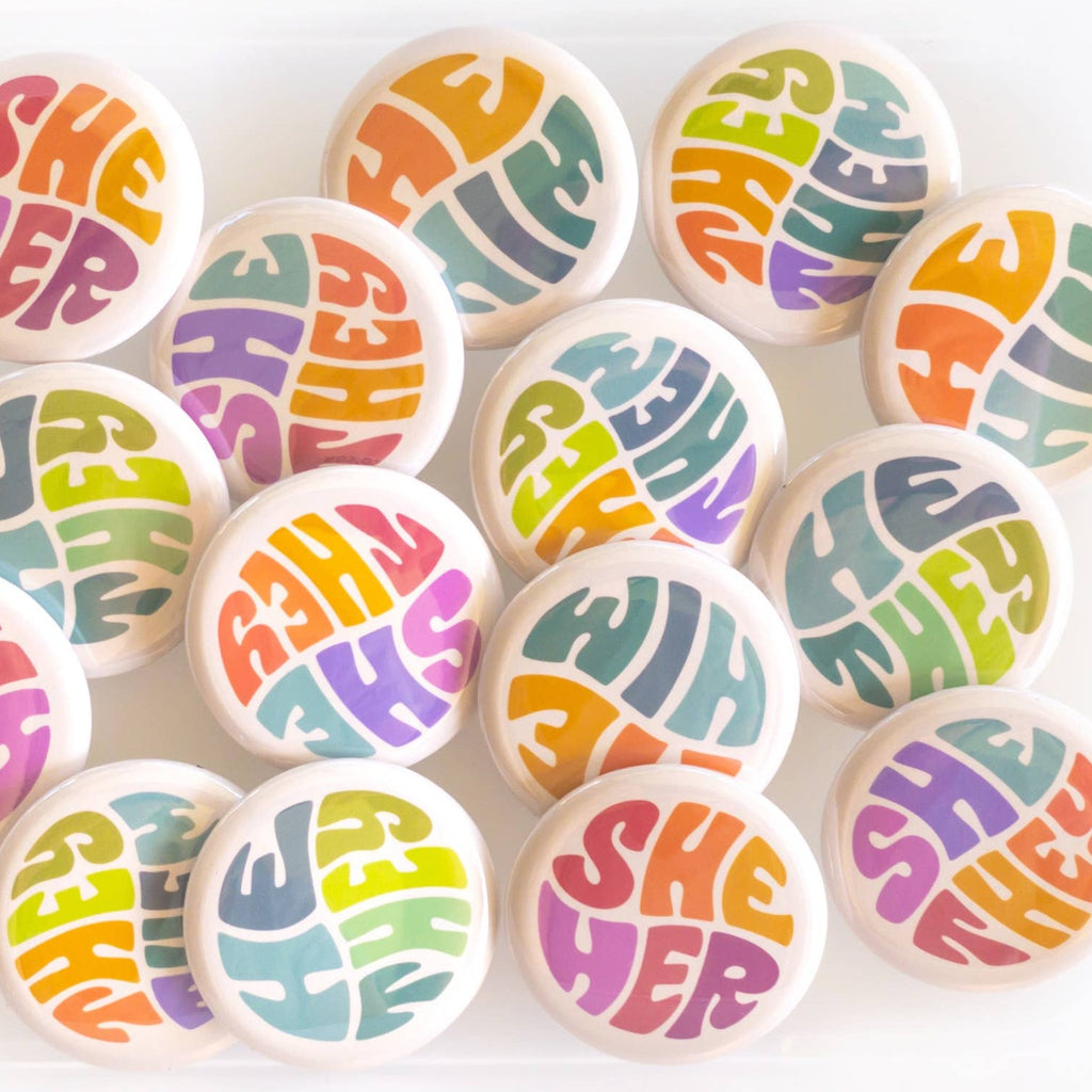 Wear your pronouns with pride with these cute retro-style buttons! This pinback button displays "He/Him" pronouns in a colorful palette. It is the perfect way to let others know how to address you and to show your support for the LGBTQ+ community!  Size: 1.25" pinback button