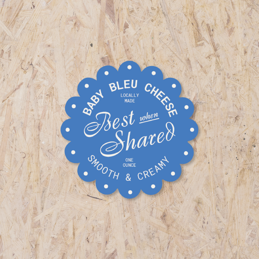 blue scalloped circle sticker reading "Baby bleu cheese, locally made, best when shared, one ounce, smooth & creamy"