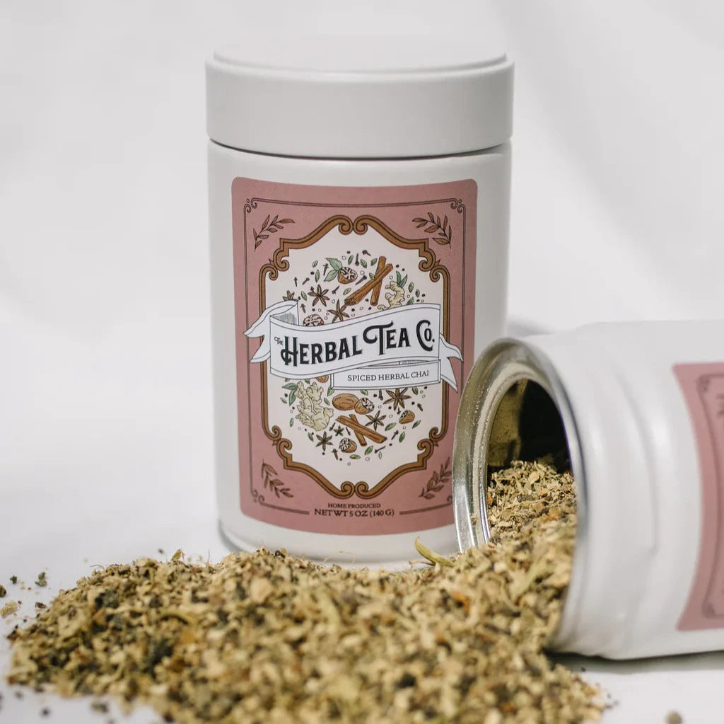 Spiced herbal chai tea spilling out of white tin with The Herbal Tea Co. logo on it