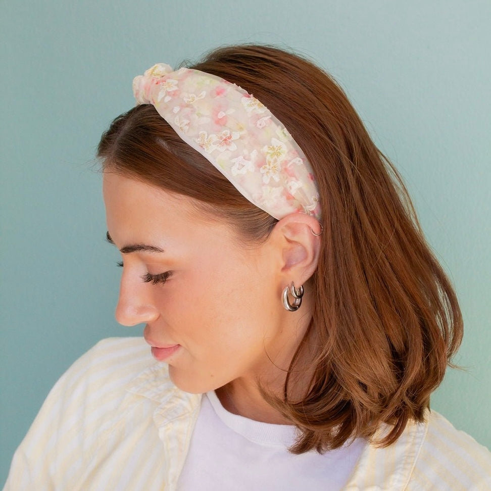 Bloom in style with our Cherry Blossom Headband! Made from sheer floral fabric, this head-turning accessory features delicate pink and white flowers and a thick top knot design. Perfect for adding a playful touch to any outfit.