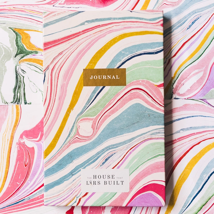 This marble hardcover journal features rainbow-colored lined pages and an exposed spine. Marbled dividers throughout the journal separate each section of colored blank pages.