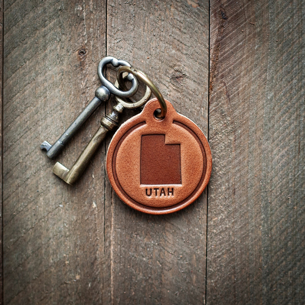 This Utah themed leather keychain comes in a perfect circle shape. Our leather keychains are cut and pressed by hand from some of the thickest and finest harness leather available, and patina beautifully as they age.

Size: 2”

Hardware: Antique Bronze 1 inch hinged keyring