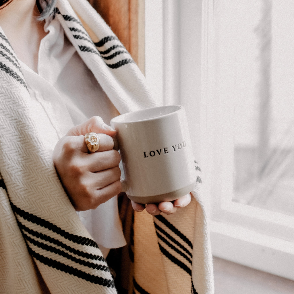 Indulge in your morning ritual with our Love You Stoneware Coffee Mug. Adorned with a heartfelt "Love you" message and crafted from cozy stoneware, this mug will quickly become a cherished part of your daily routine. With its natural colors and elegant black lettering, it adds a touch of sophistication to your kitchen decor. Sip your favorite brew in style and show your love at the same time.