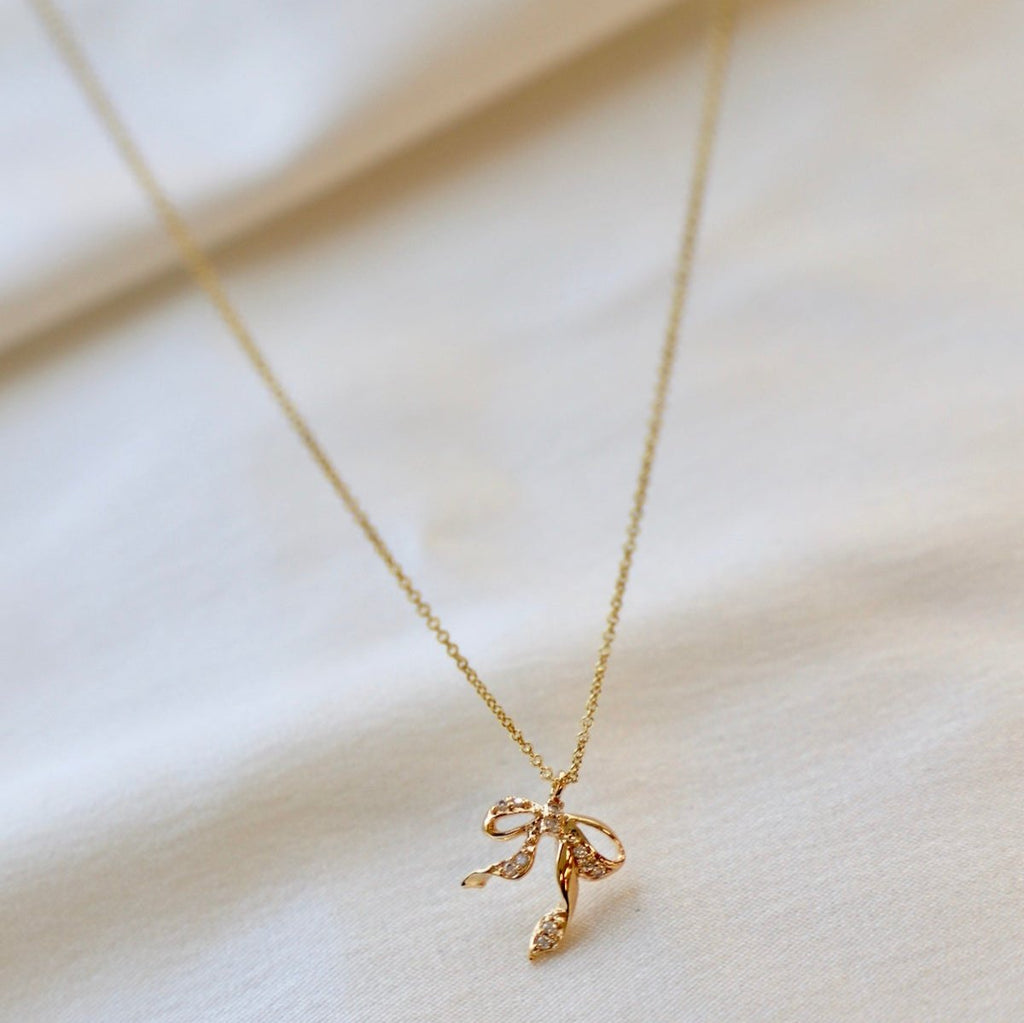 This CZ Bow Necklace features a bow pendant charm detailed with cz's for a timeless and elegant look. The perfect accessory to add a sweet and delicate, yet eye-catching touch to your look.