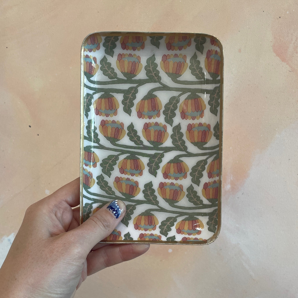 Add a touch of whimsy to your serving game with our Enameled Stainless Steel Tray adorned with charming flowers on a winding vine. Sturdy and stylish, this tray is perfect for hosting or everyday use. Serve up some smiles and style with this unique piece.