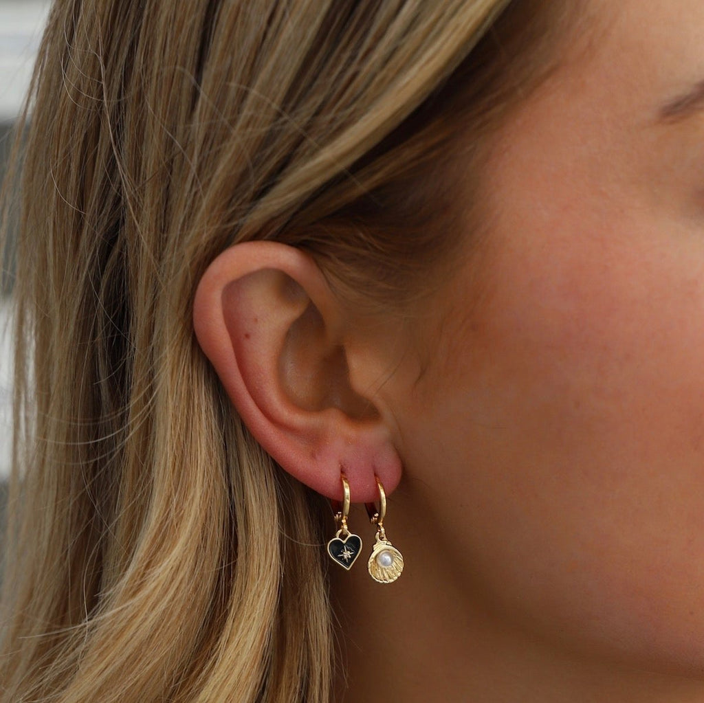 Upgrade your earring game with our&nbsp;Black Heart Huggies. These 14k gold plated huggie earrings feature a sleek black enamel heart, adding a chic and modern touch to any outfit.