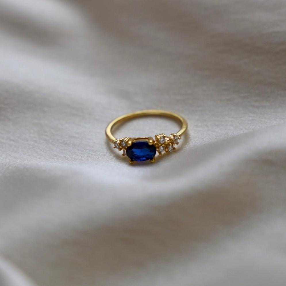 This Midnight Sky Ring is designed to make an impression with its striking oval sapphire center, surrounded by dazzling clear cubic zirconia accents. A piece that will make a shining statement