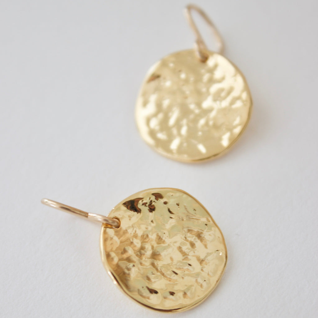 These Hammered Medallion Earrings add a touch of whimsy to any outfit. With their unique hammered design, they are sure to catch anyone's eye. Make a statement with these playful and quirky earrings.