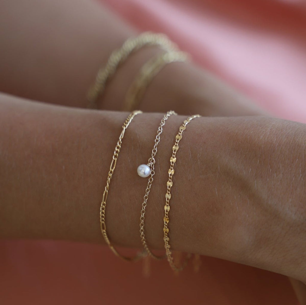 The Malibu Chain Bracelet features a delicate yet eye-catching gold-filled chain that adds a touch of elegance to any outfit. Its versatile design allows for easy layering, making it perfect for everyday wear.