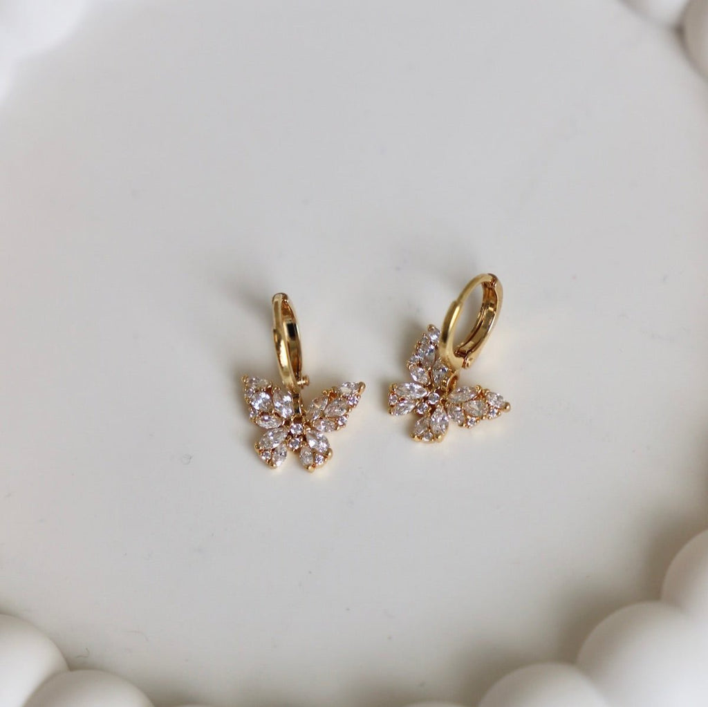 Effortlessly elevate your look with this Ara Butterfly Huggies. These stunning huggie earrings feature sparkly cubic zirconia butterflies that add a touch of delicate elegance to any outfit. Made with high-quality materials, they provide a comfortable and secure fit while exuding a timeless glamour.