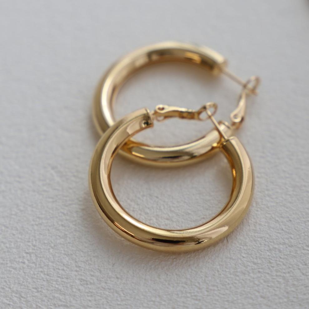 This medium thick hoop puts a modern spin on the classic hoop. We love to wear this sleek look on its own or with a simple stud. In gold.