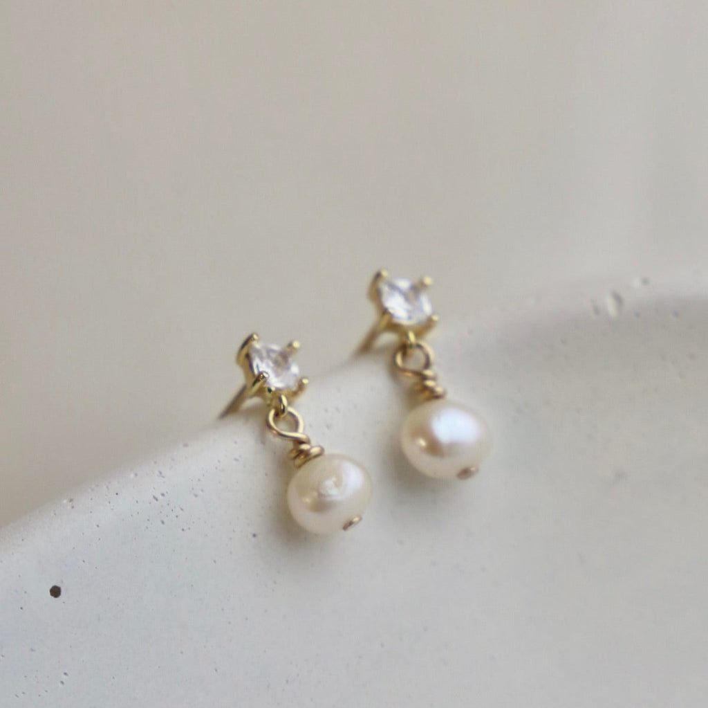 Add a touch of elegance with Claire Pearl Studs. These miniature cz square studs feature a freshwater pearl drop that will elevate any outfit. Perfect for those who love a hint of quirk and sophistication.