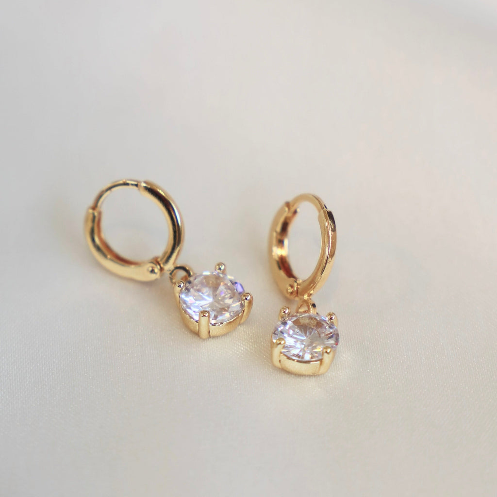 This CZ gold Round Huggie will be a shiny and classic addition to your earring collection. These earrings are perfect to wear alone or stack with some hoops to create a dimensional earring look