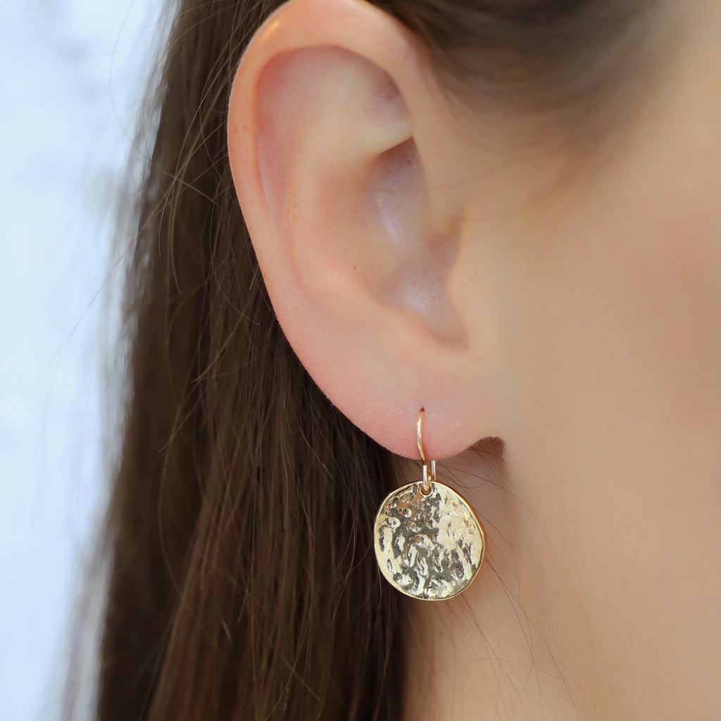 These Hammered Medallion Earrings add a touch of whimsy to any outfit. With their unique hammered design, they are sure to catch anyone's eye. Make a statement with these playful and quirky earrings.