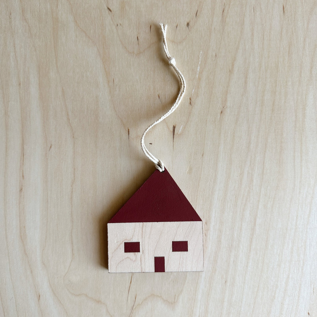 wooden house ornament with the windows, roof, and door painted maroon