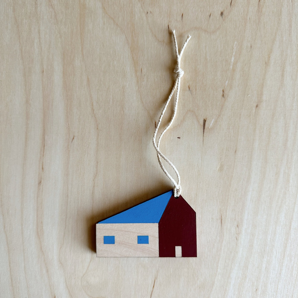 wooden house ornament with blue windows and roof and maroon wall