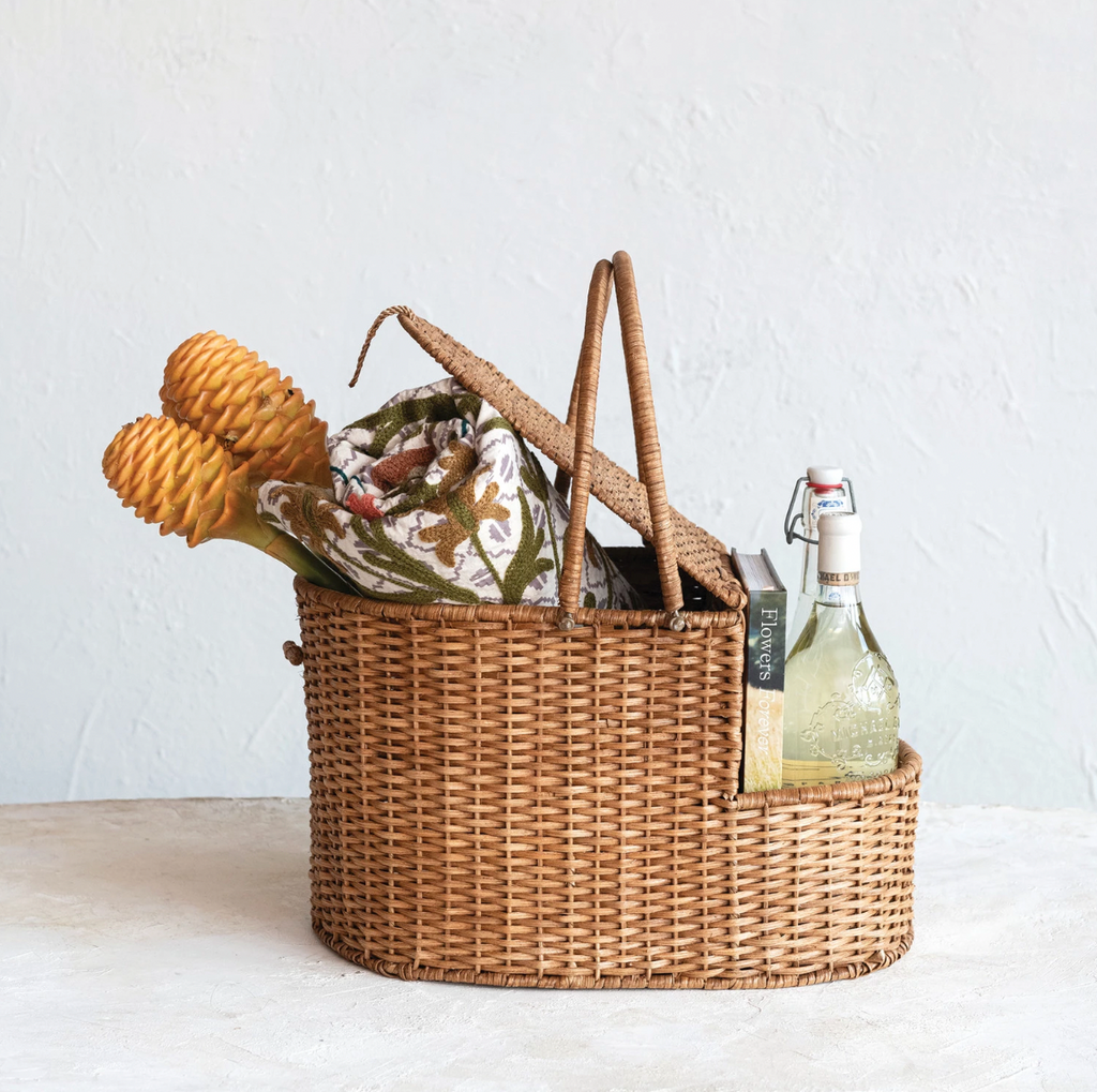 This picnic basket is a beautiful and functional piece that will enhance the home with its natural charm. The picnic basket is made of rattan wicker, an eco-friendly and durable material handwoven by skilled artisans. The wicker has an oval shape and a natural color that adds texture and warmth to any space. The picnic basket also has an open side compartment that provides extra storage space for the items. The picnic basket has two handles that make it easy to carry and move. 17"L x 12"W x 10"H