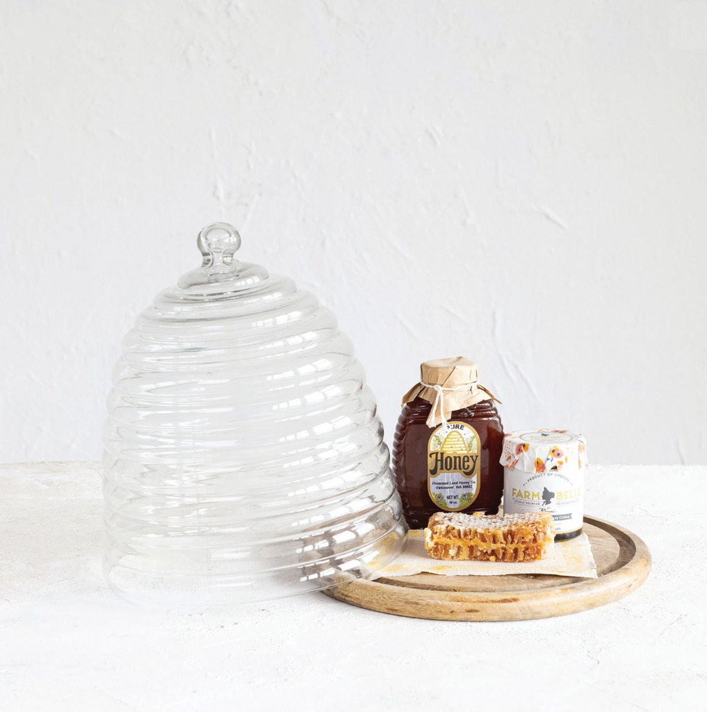 Introducing our set of two recycled glass beehive cloches with a mango wood base - the perfect eco-friendly addition to your home. Each beehive-shaped cloche is handcrafted from recycled glass and paired with a sustainably-sourced mango wood base. Keep your food and decor fresh while helping to save the bees! 11" Round x 11-1/2"H