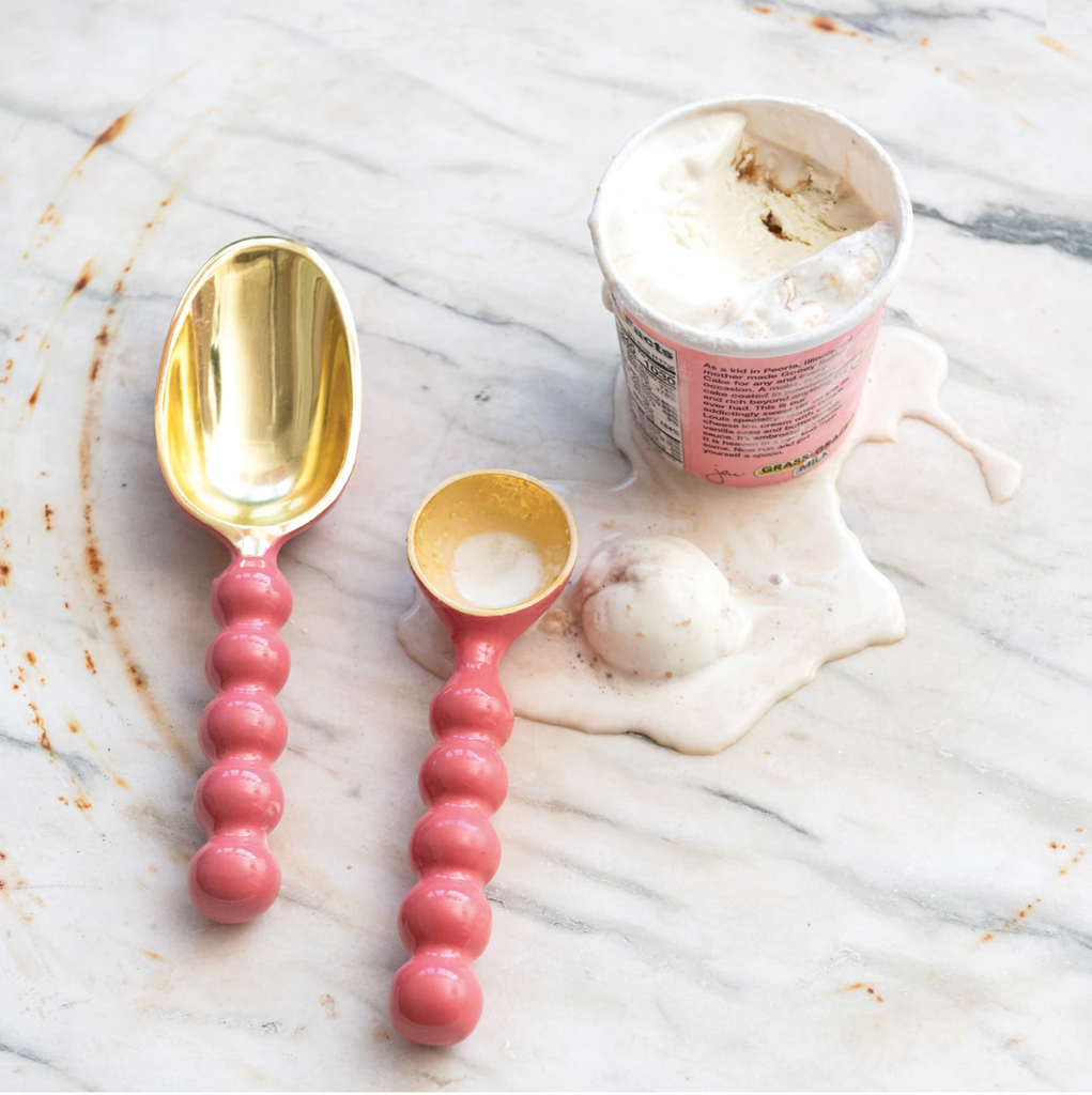 This enameled aluminum scoop is a cute and stylish piece that will add some flair and color to the kitchen. This scoop has a pink color and a gold finish, creating a contrast and a harmony between the metal and the enamel. It has a curved handle and a round bowl, which are smooth and comfortable to hold and use. Use it to scoop ice cream, candy, nuts, or popcorn, or as a decorative item or a gift. 9-1/2"L