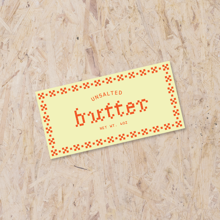 yellow rectangle sticker reading "Unsalted Butter Net Wt. 4oz" with red cross-stitch details