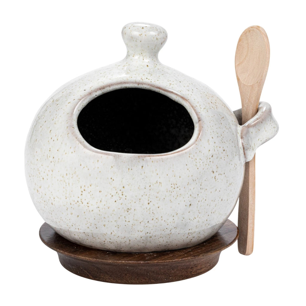 This stoneware salt jar with a wooden spoon and coaster in cream is a beautiful and functional piece that will enhance cooking and dining experience. It features a stoneware salt jar with a reactive glaze in a cream color that creates a smooth and glossy finish. The salt jar has a round shape and a lid with a knob that makes it easy to open and close. The set also includes a wood spoon and a coaster that complement the salt jar and protect the table from scratches.