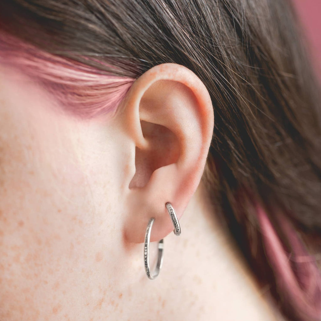 Much like the classic hoop, these hoops have enough texture and detail to stand out. One piece sterling silver half round wire is textured by hand with a line pattern. Hoops are medium size, about 1" diameter 14 Gauge wire thickness with texture Polished finish.