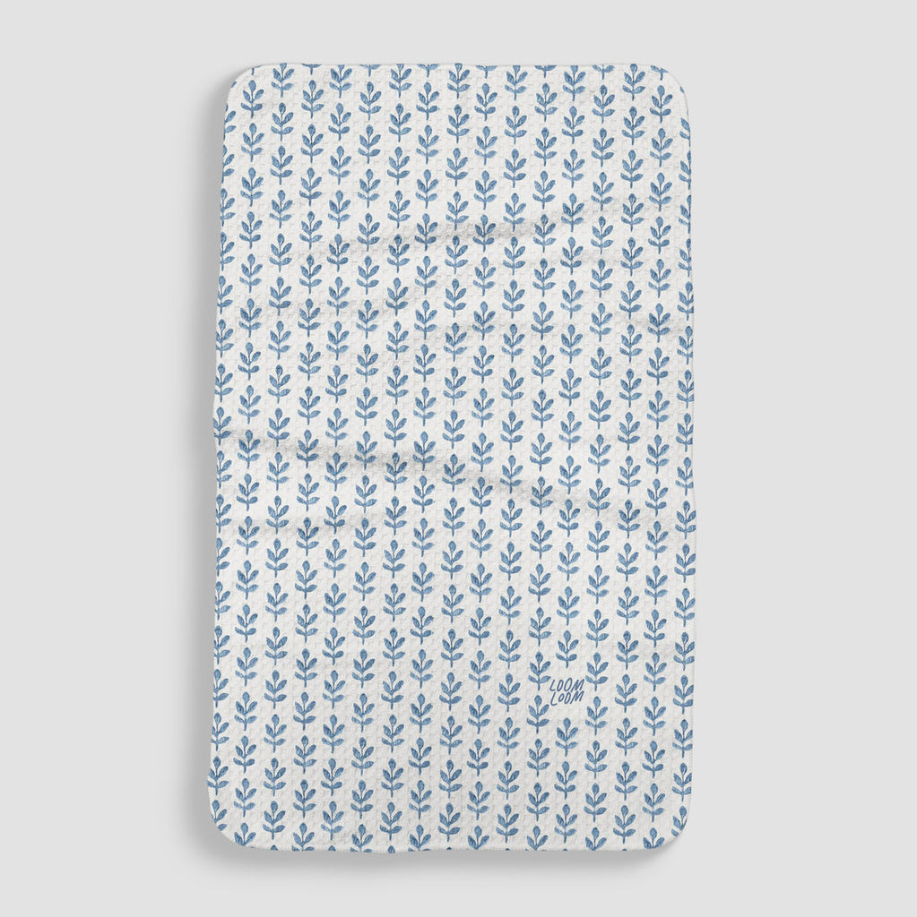 white tea towel covered in a blue stem pattern