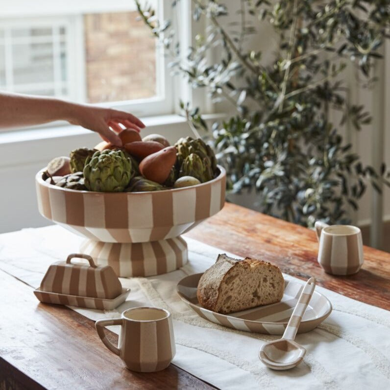 Elevate your dining or coffee table with the simple, artful design of the medium Botera Platter. Featuring a food-safe finish on top of neutral, textured ceramic with chunky, speckled white glazed stripes, this serving dish coordinates with the full Botera collection & stands out among dinnerware with its minimalist sensibility. We recommend handwashing to protect finish