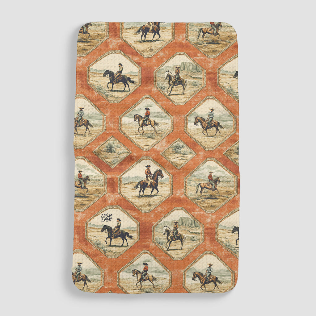 rust orange tea towel with vintage cowboys on horseback in frames