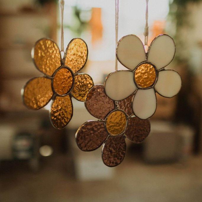 The daisy is made of six hand cut and shaped pieces of glass. Using transparent rough rolled textured glass in the colors of amber orange for the petals and amber yellow for the center. Welded together with a lead and tin solder. 