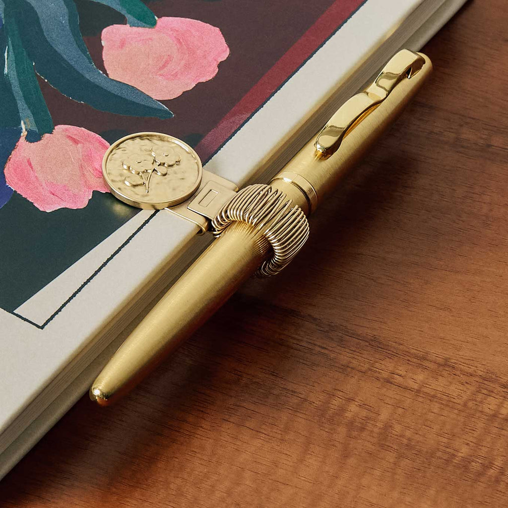 Keep your pen and your pages together forever. Papier's brass pen clips can be attached the cover of any of our notebooks, journals or planners. The clip is adjustable, with a stretchy slot to accommodate pens and pencils of all sizes, so you'll never misplace them again. A wonderful gift for any paper person.