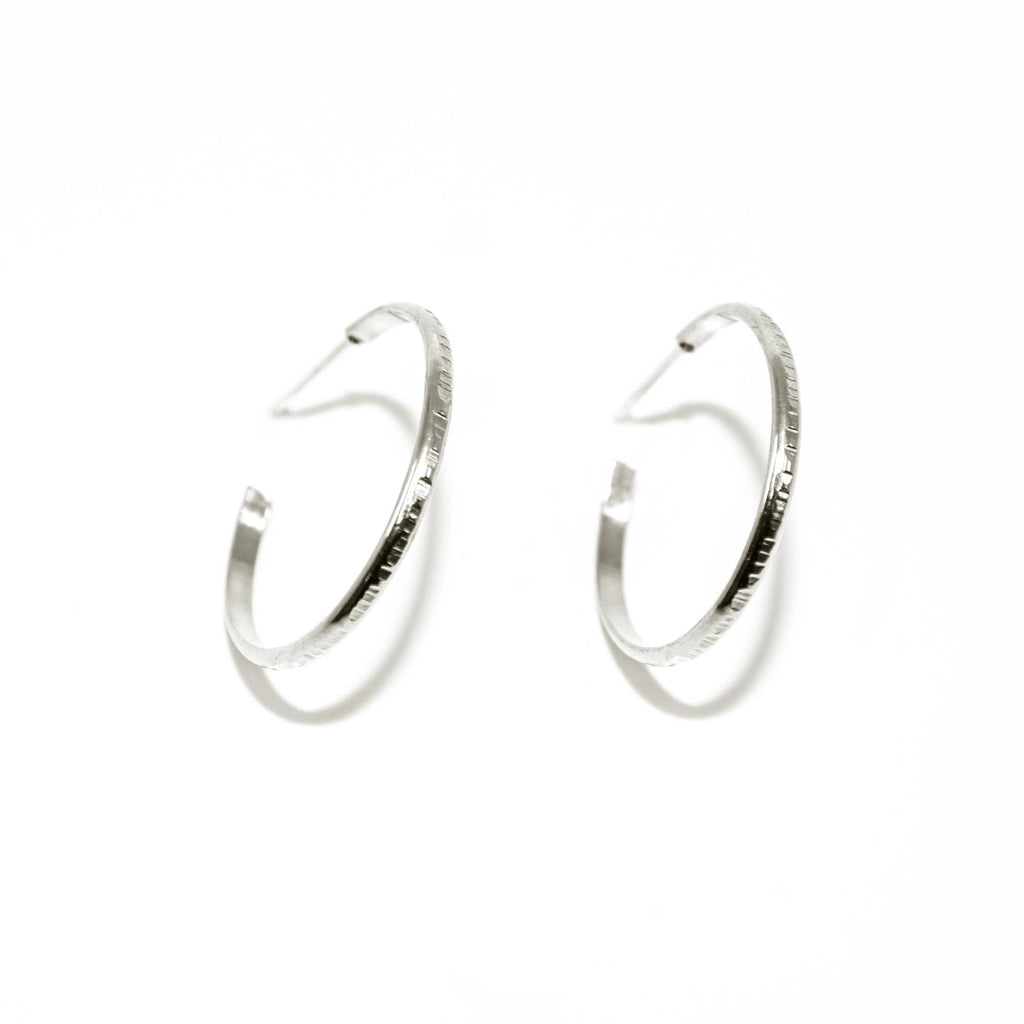 Much like the classic hoop, these hoops have enough texture and detail to stand out. One piece sterling silver half round wire is textured by hand with a line pattern. Hoops are medium size, about 1" diameter 14 Gauge wire thickness with texture Polished finish.