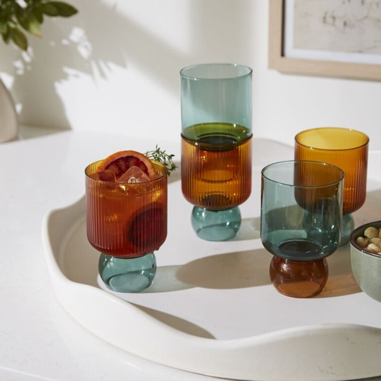 Full of fun, clever details &amp; bold color, the Felix Drinkware brings an elevated yet playful look to tableware. Handmade from lightweight, solid borosilicate glass, this drinking glass is two-toned with a ribbed amber top &amp; smooth, ball-shaped turquoise foot. Style this chic vessel on a bar cart or open kitchen shelving to show off its trendy, unique design while adding a pop of color to home decor.&nbsp;