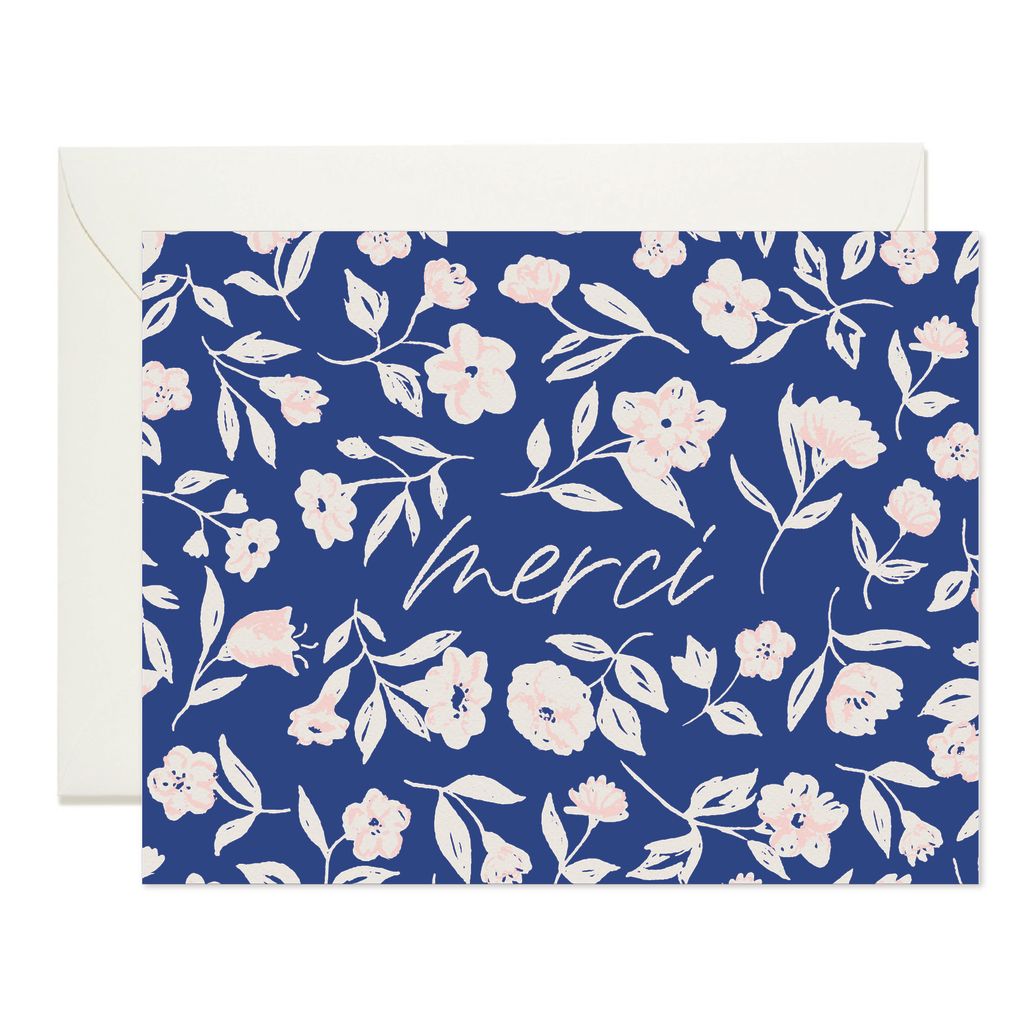 blue card reading "merci" with white and pink flowers