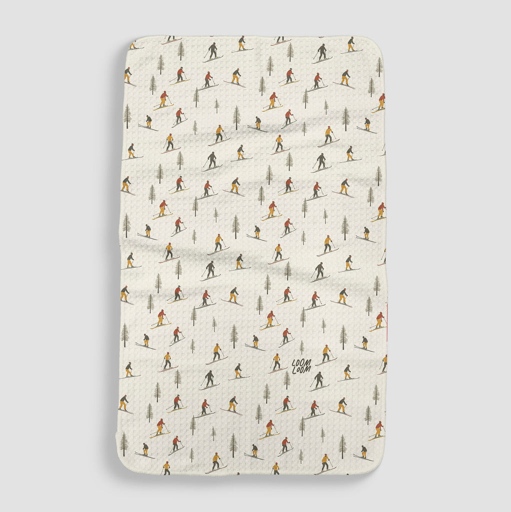 white tea towel with colorful skiers and pine trees