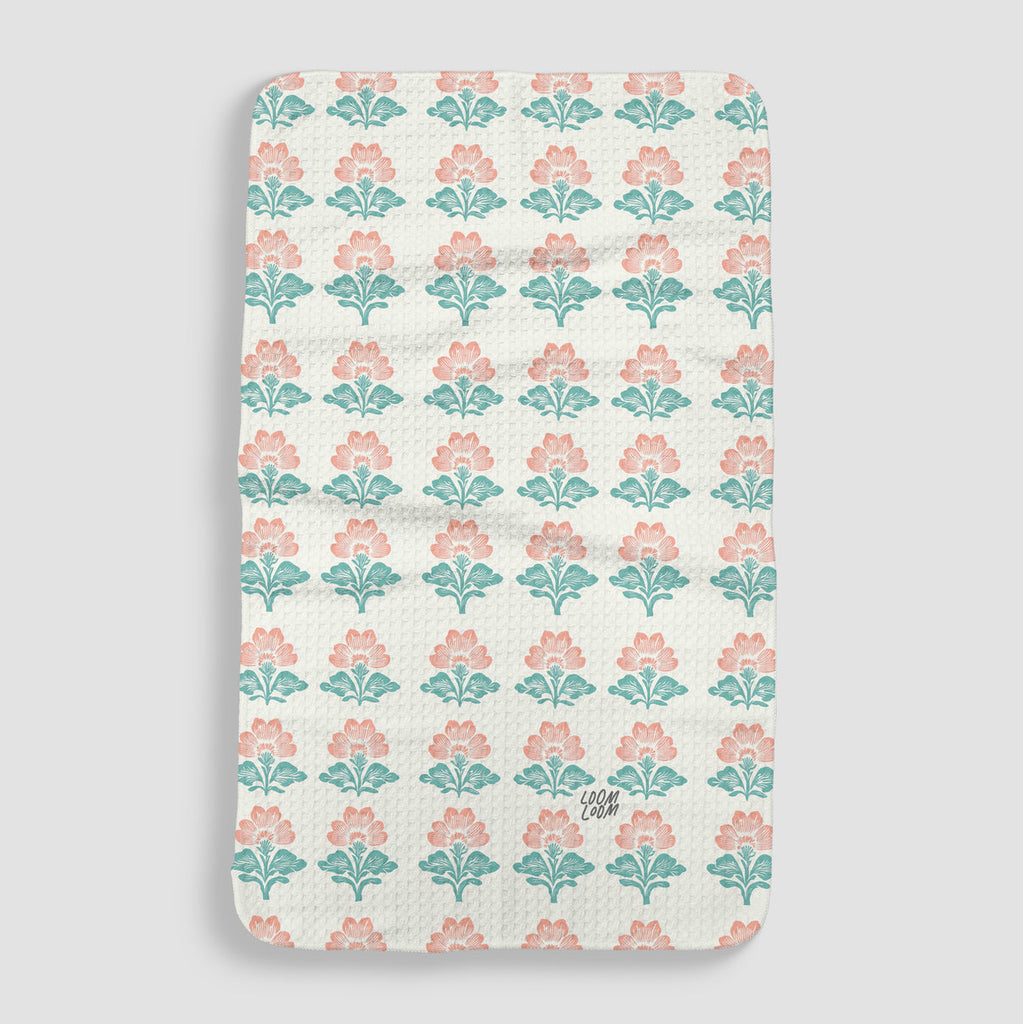 white/cream tea towel with a repeated pattern of teal and pink flowers