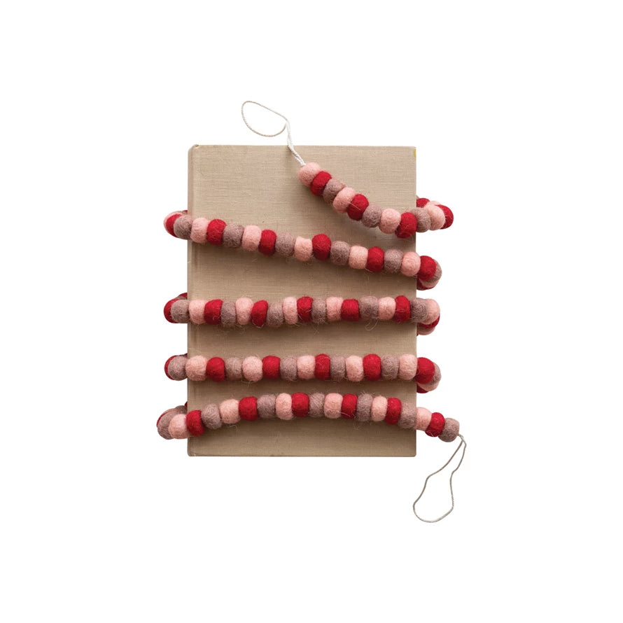 This handmade wool felt ball garland is a celebration of love, with its red, pink, and rose-colored balls creating a tender atmosphere wherever it's placed. At 72 inches long and half an inch high, it's a versatile decoration that can be draped over a mantelpiece, around a bed frame, or along a table, infusing the space with a sense of romance and care.