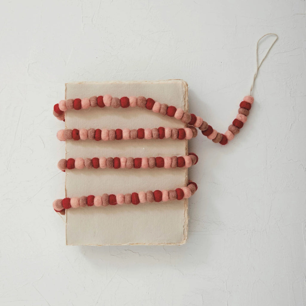 This handmade wool felt ball garland is a celebration of love, with its red, pink, and rose-colored balls creating a tender atmosphere wherever it's placed. At 72 inches long and half an inch high, it's a versatile decoration that can be draped over a mantelpiece, around a bed frame, or along a table, infusing the space with a sense of romance and care.