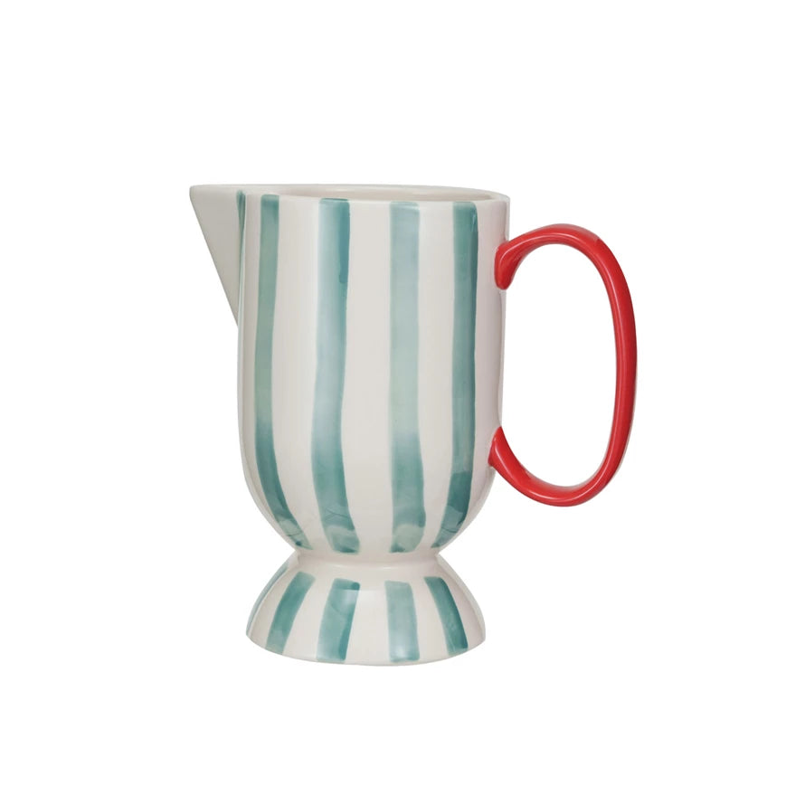 This vibrant footed pitcher, with its hand-painted stripes of red, aqua, and cream, captures the essence of artisanal craftsmanship. The stoneware construction ensures durability, while the food-safe designation promises safe use at every meal.