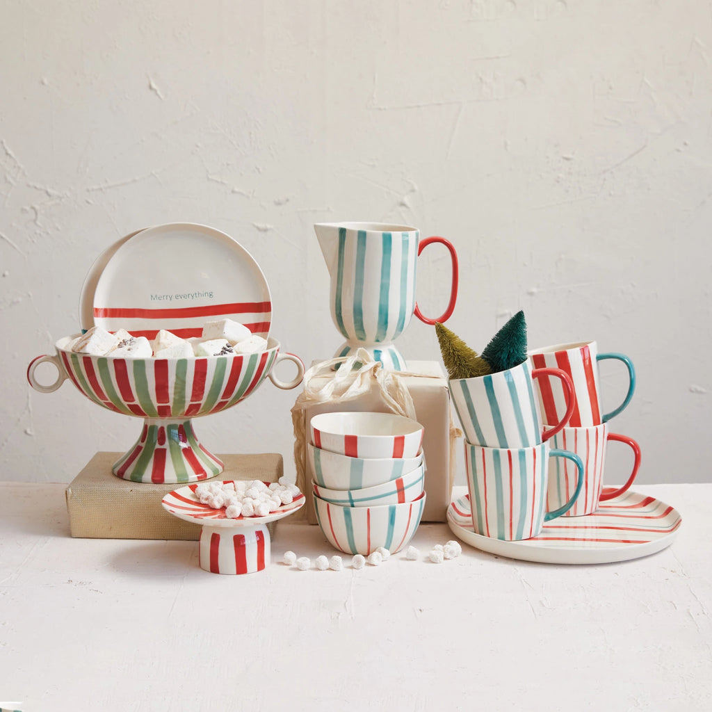 This vibrant footed pitcher, with its hand-painted stripes of red, aqua, and cream, captures the essence of artisanal craftsmanship. The stoneware construction ensures durability, while the food-safe designation promises safe use at every meal.