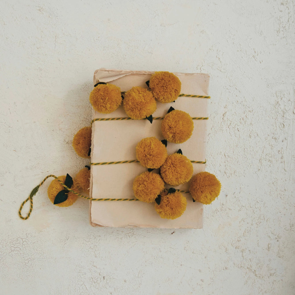 This acrylic pom pom garland with wool felt leaves is a delightful mix of texture and color. The mustard pom poms bring a cheerful vibrancy, while the green wool felt leaves add a touch of organic elegance.